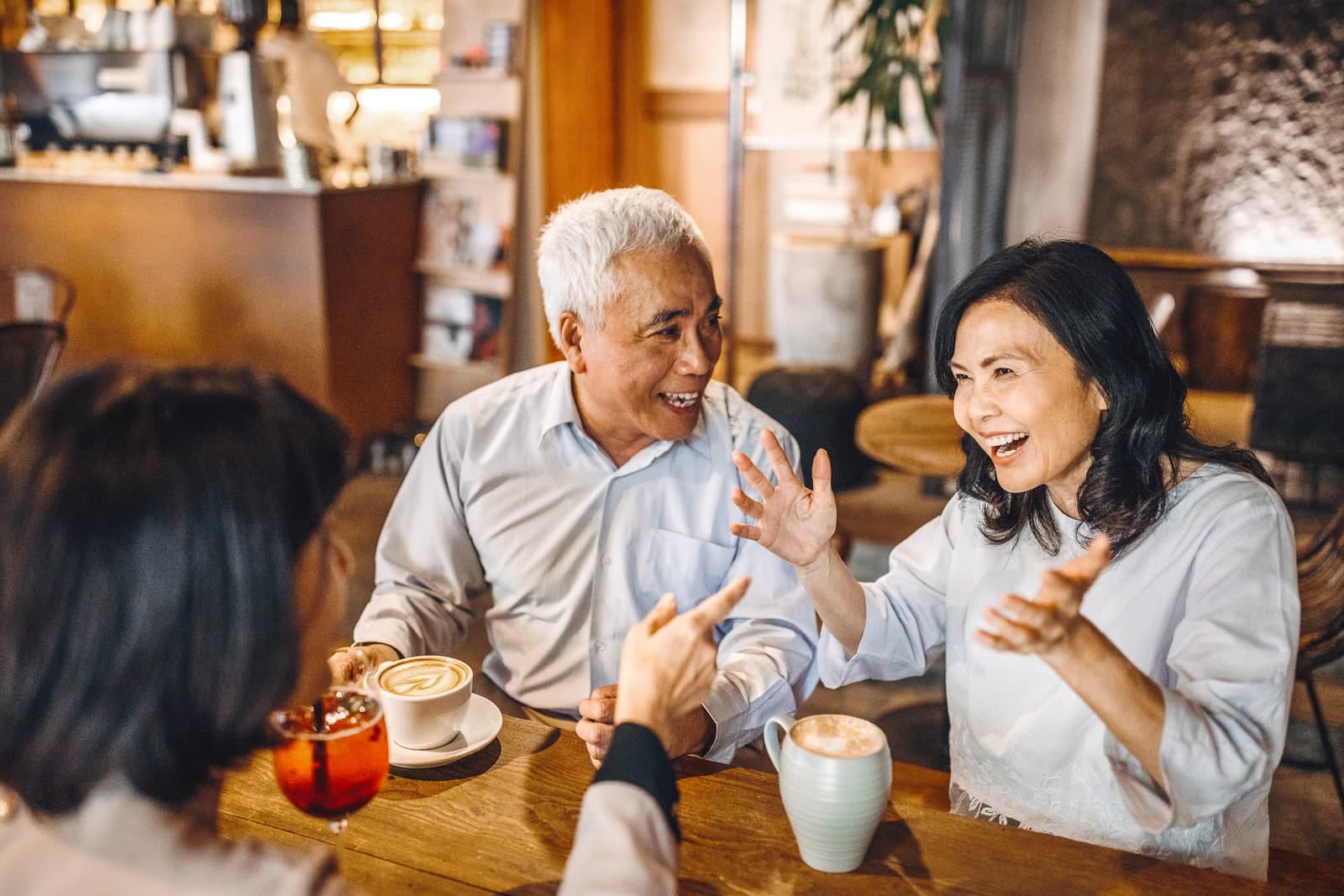 Friends laughing and talking over coffee in a café